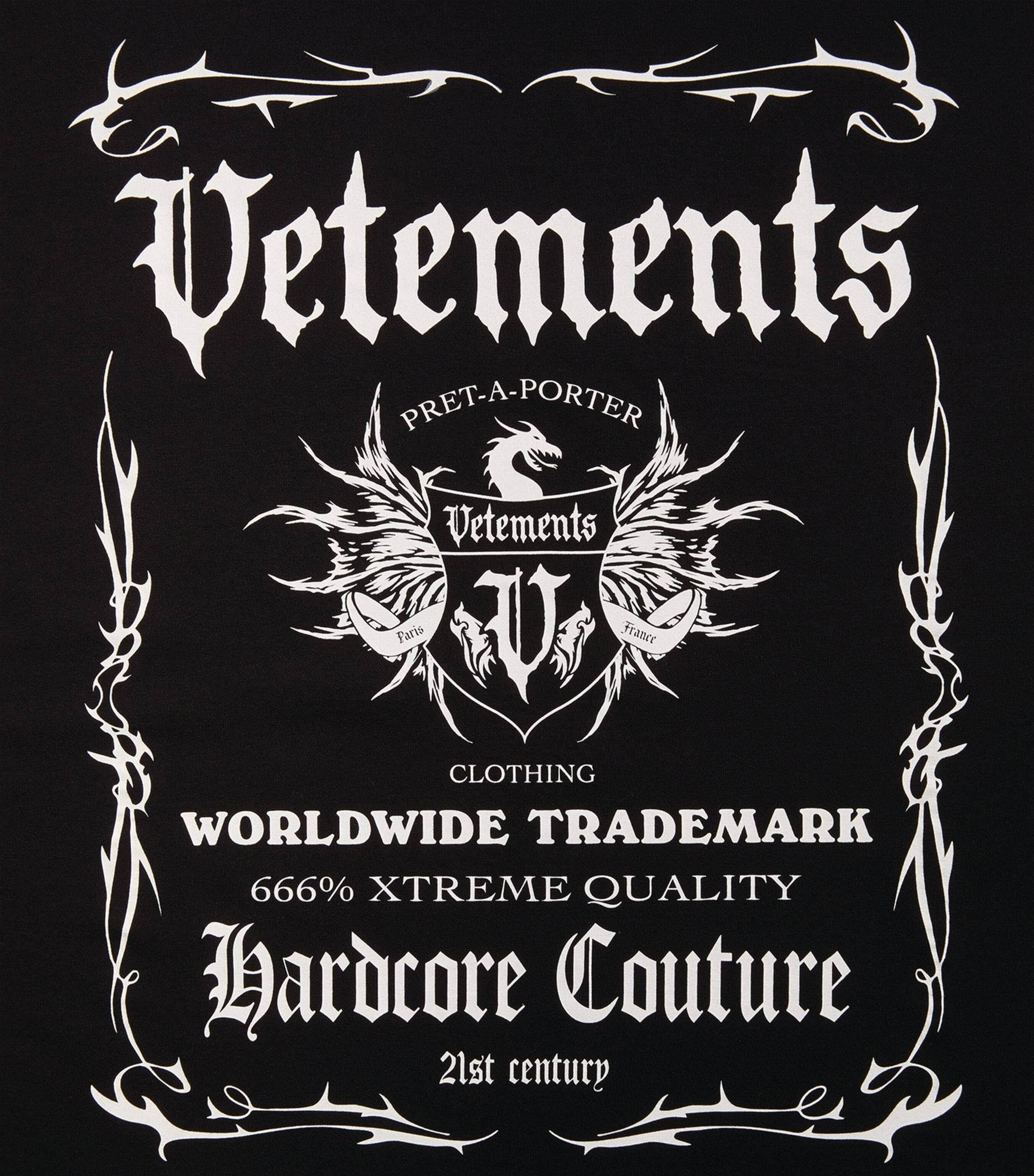 Vetements 桌布 壁紙 — 黑色背景，帶有華麗的白色哥德式字體和帶有龍和翅膀的紋章，用於Vetements服裝品牌。