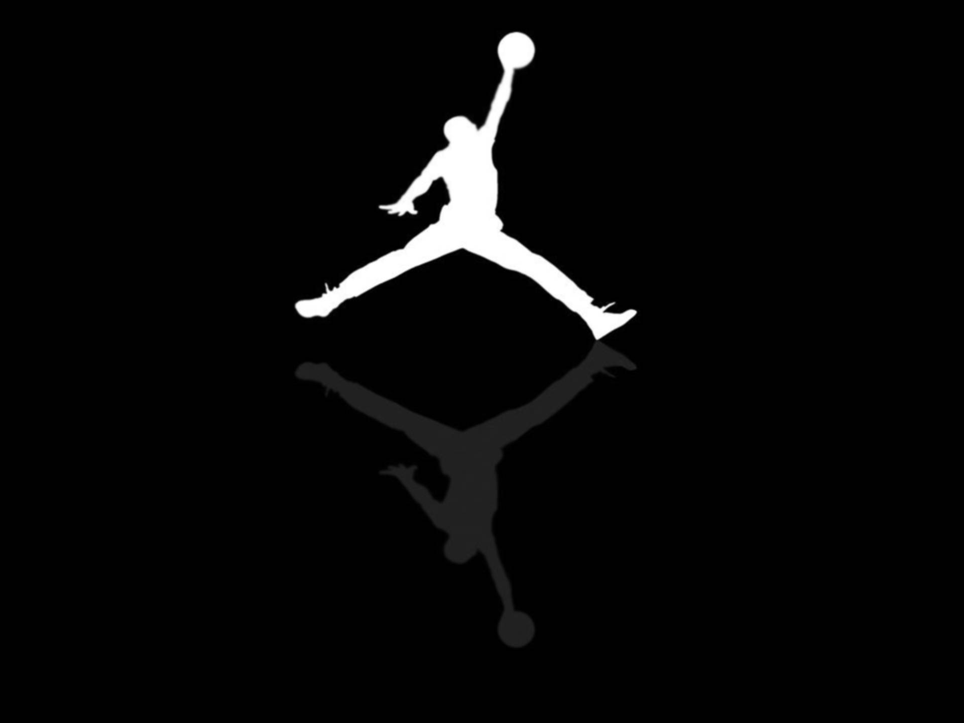 Air Jordan 桌布 壁紙 — 黑色背景上，一個籃球運動員在半空中灌籃的鮮明白色剪影，下方有鏡像倒影。
