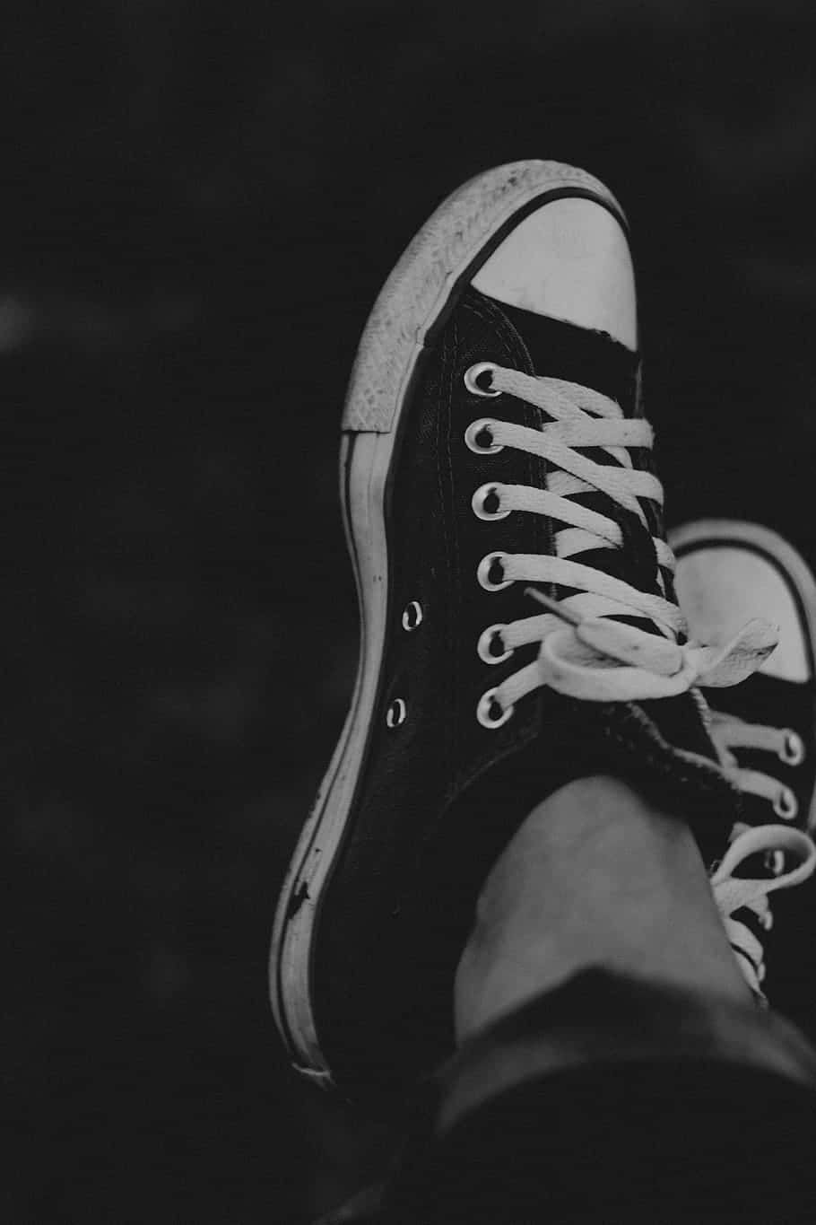 黑色 桌布 壁紙 — 黑色背景上，一雙磨損的Converse運動鞋，白色鞋帶和橡膠鞋底的黑白特寫。