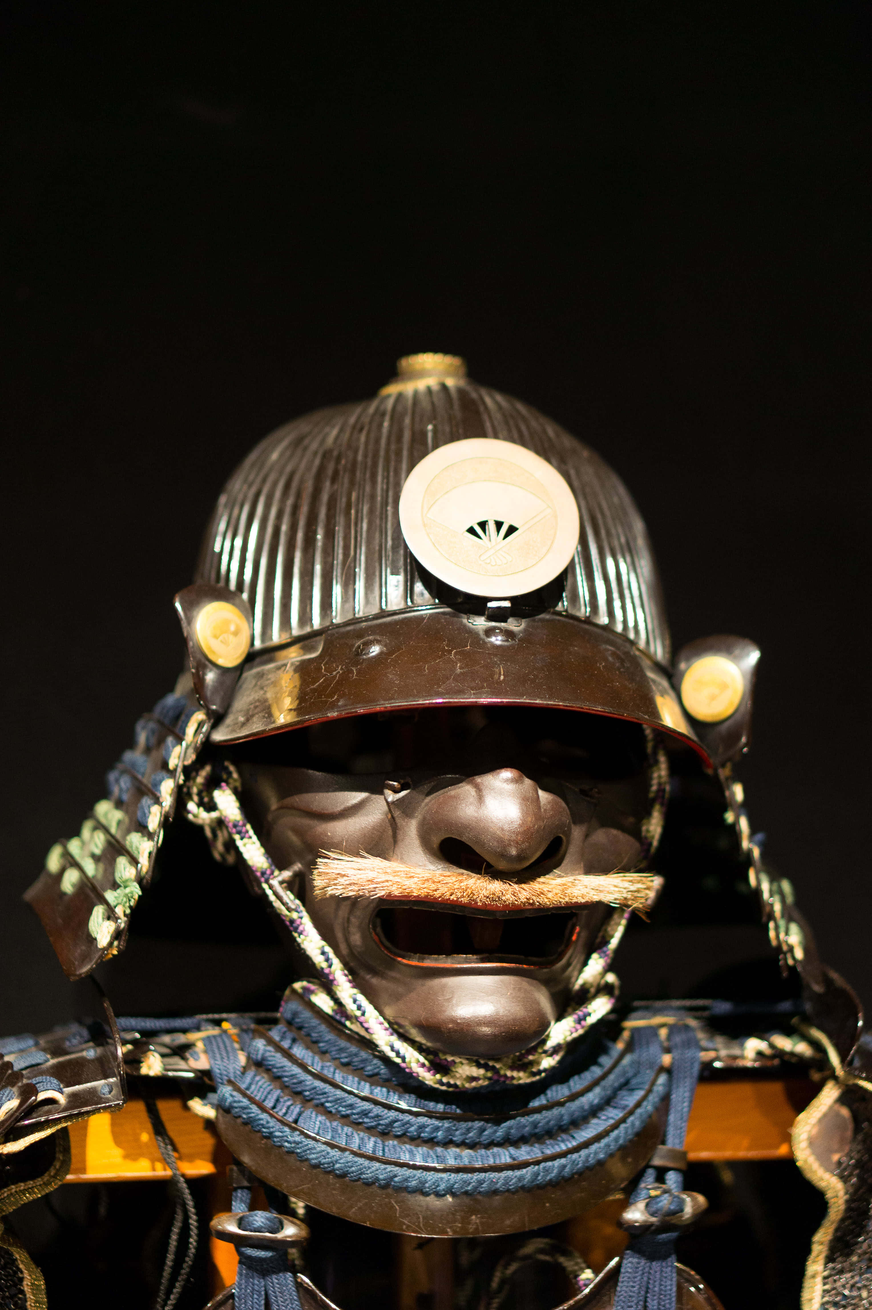 Samurai Armor 桌布 壁紙 — 黑色背景上，帶有華麗面罩和藍色繩索的詳細武士頭盔特寫。