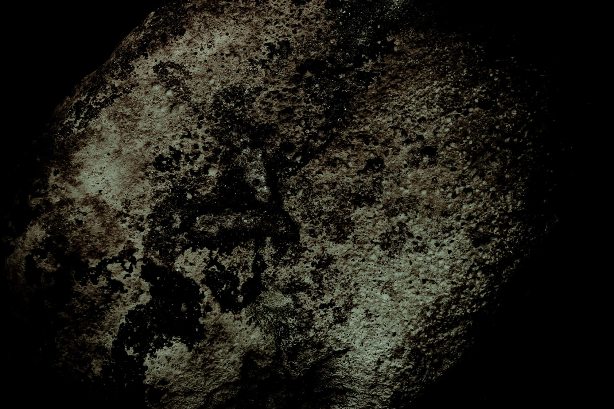 Dark Rock 桌布 壁紙 — 黑色背景上，粗糙紋理岩石表面的特寫，帶有深色斑塊和微妙的綠色亮點。