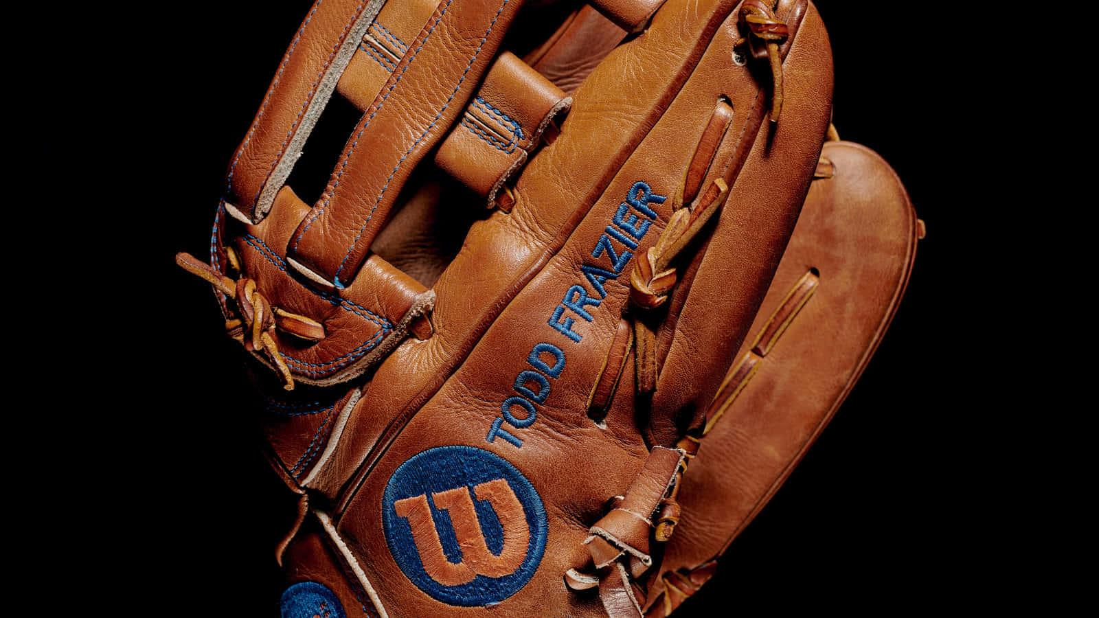 Baseball Gloves 桌布 壁紙 — 黑色背景上印有「TODD FRAZIER」和Wilson標誌的棕色皮革棒球手套特寫。