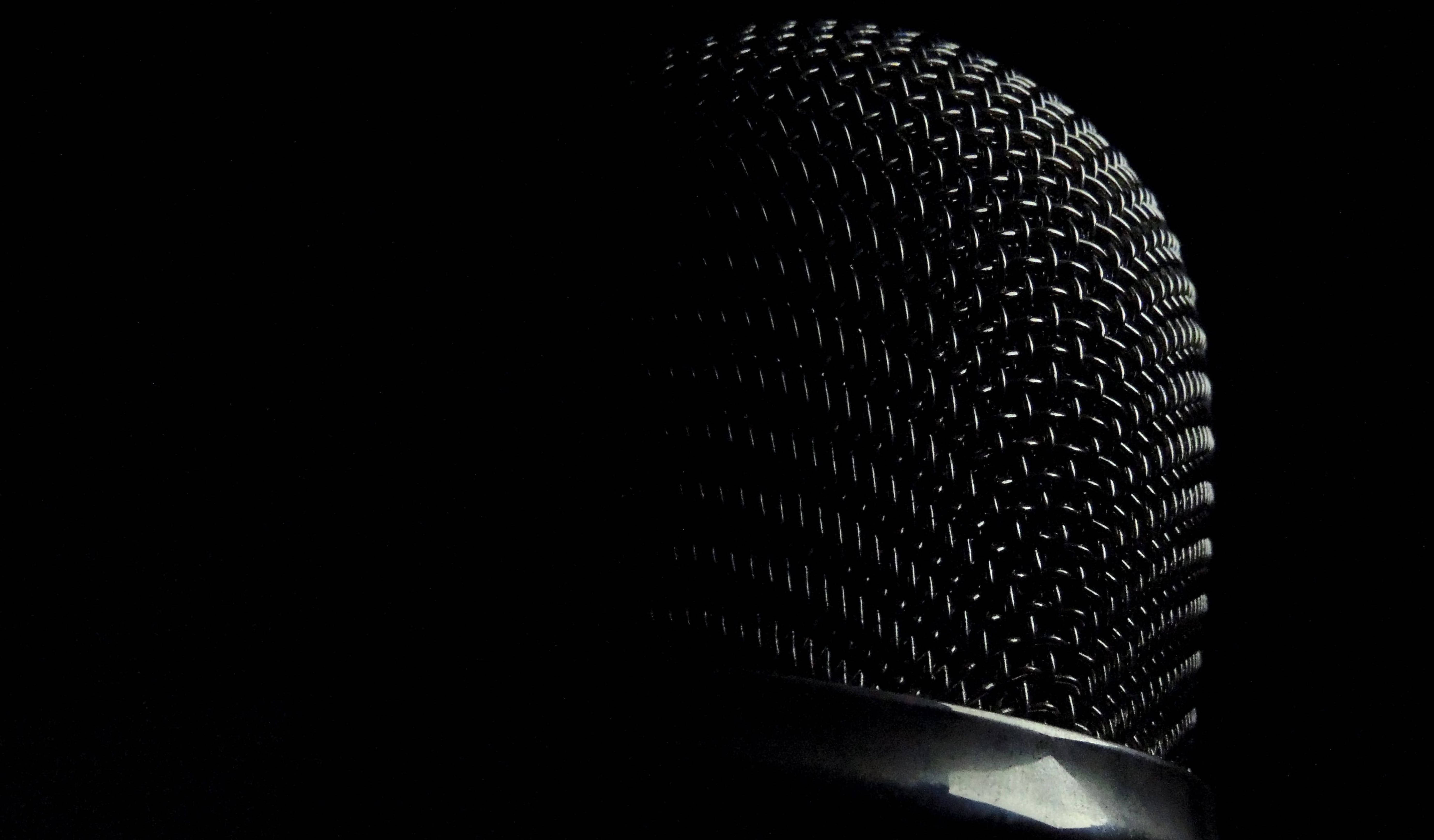 Microphone 桌布 壁紙 — 黑色背景上單一燈光照亮的麥克風格柵特寫。