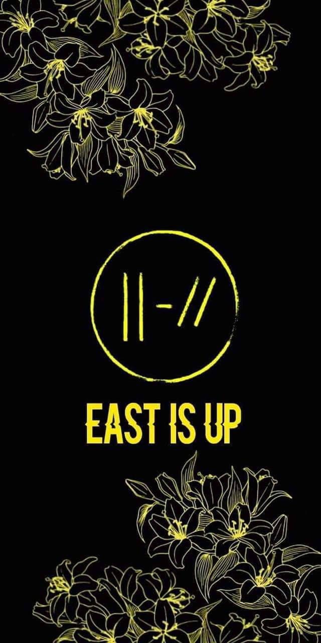 Twenty 桌布 壁紙 — 黑色背景上大膽的黃色花卉線條藝術和文字，中間有「EAST IS UP」。