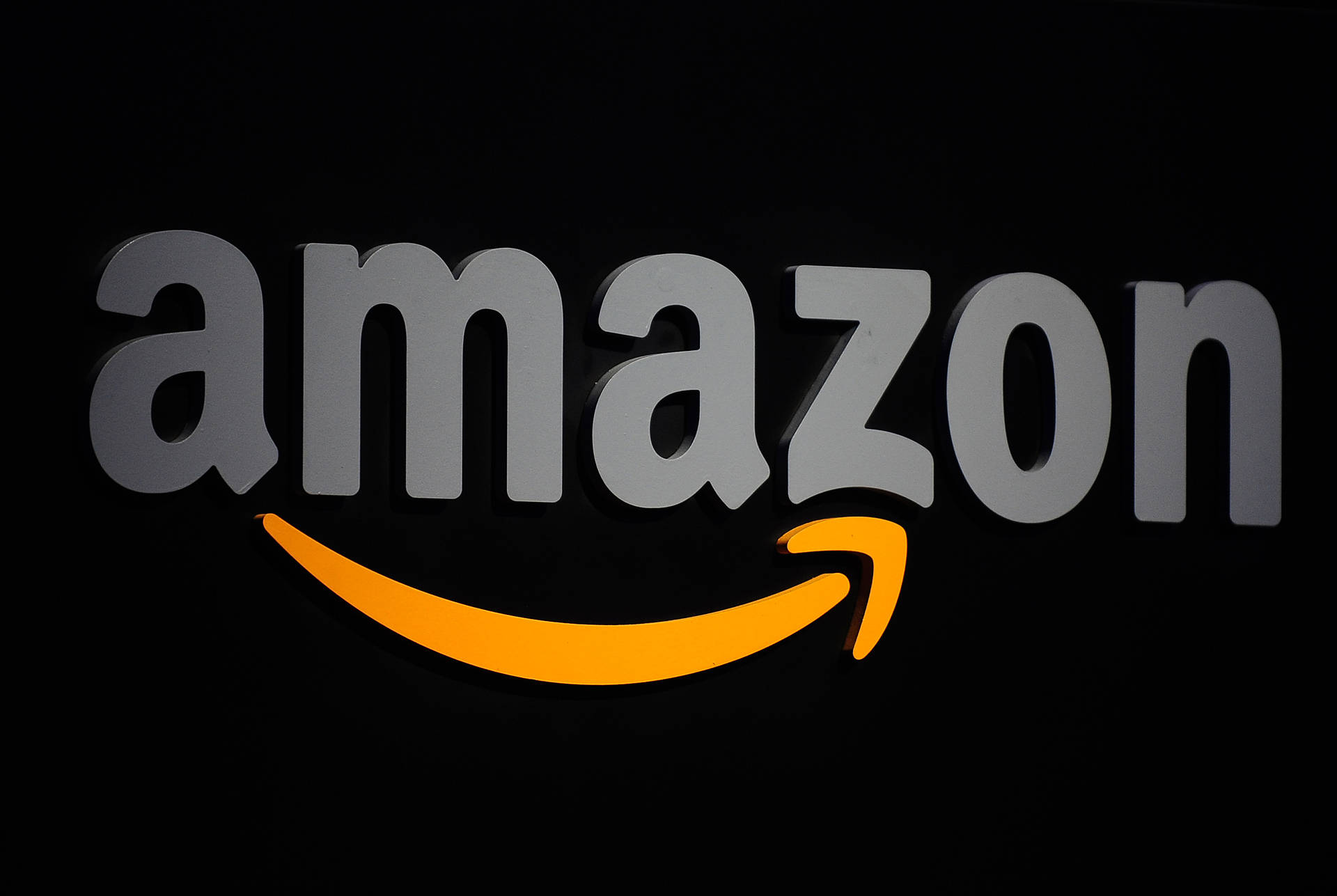 黑色背景上帶有灰色字母和橙色箭頭的Amazon標誌。 — 亞馬遜 GIF 壁紙