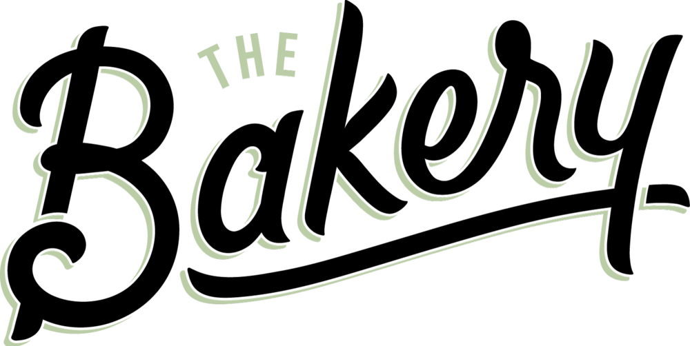 烘焙坊 桌布 壁紙 — 黑色背景上帶有裝飾性花飾的「The Bakery」優雅淺綠色草書標誌。