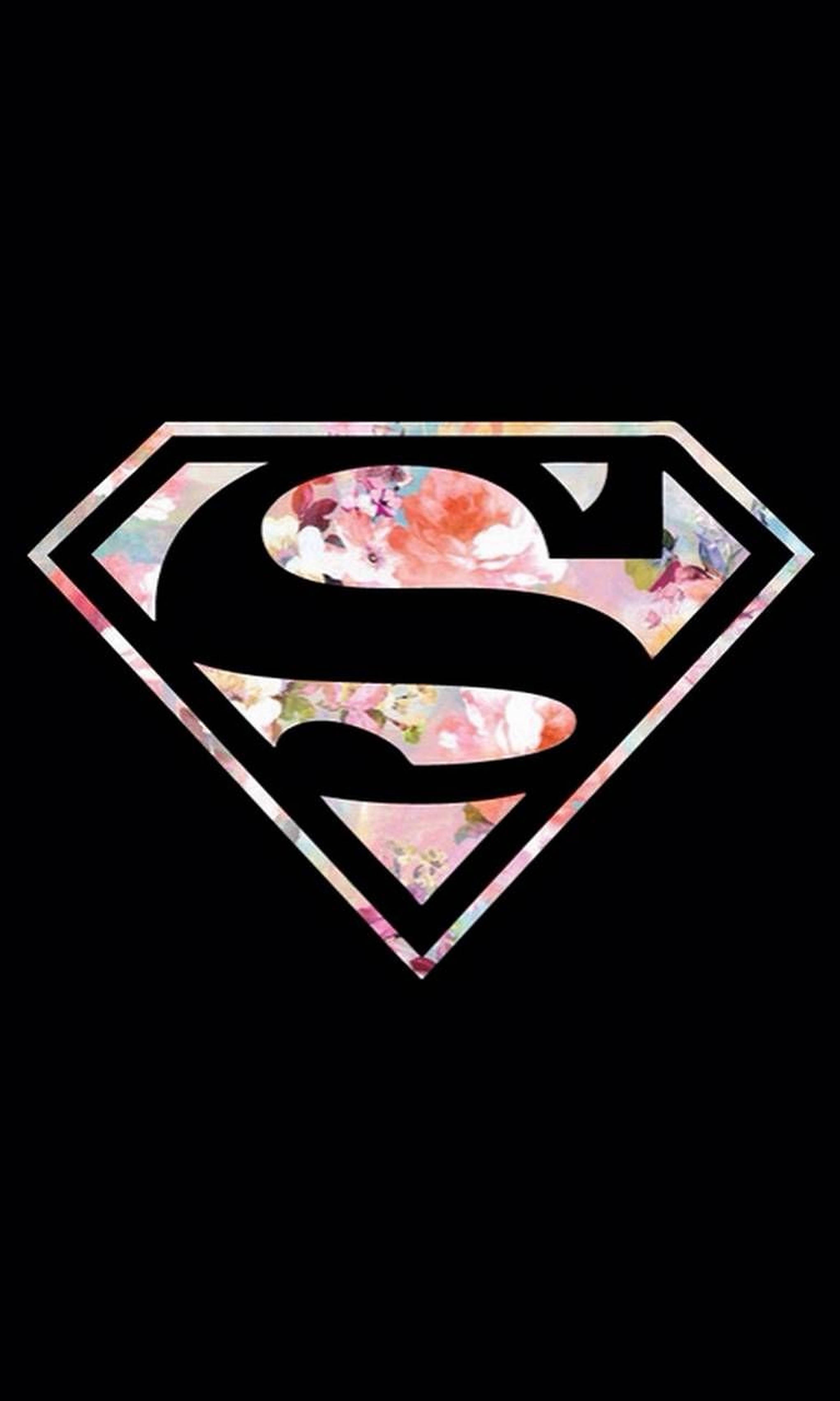Superwoman 桌布 壁紙 — 黑色背景上有一個超人標誌，裡面填滿了柔和的粉紅色和蜜桃色花卉圖案，並帶有閃閃發光的邊框。