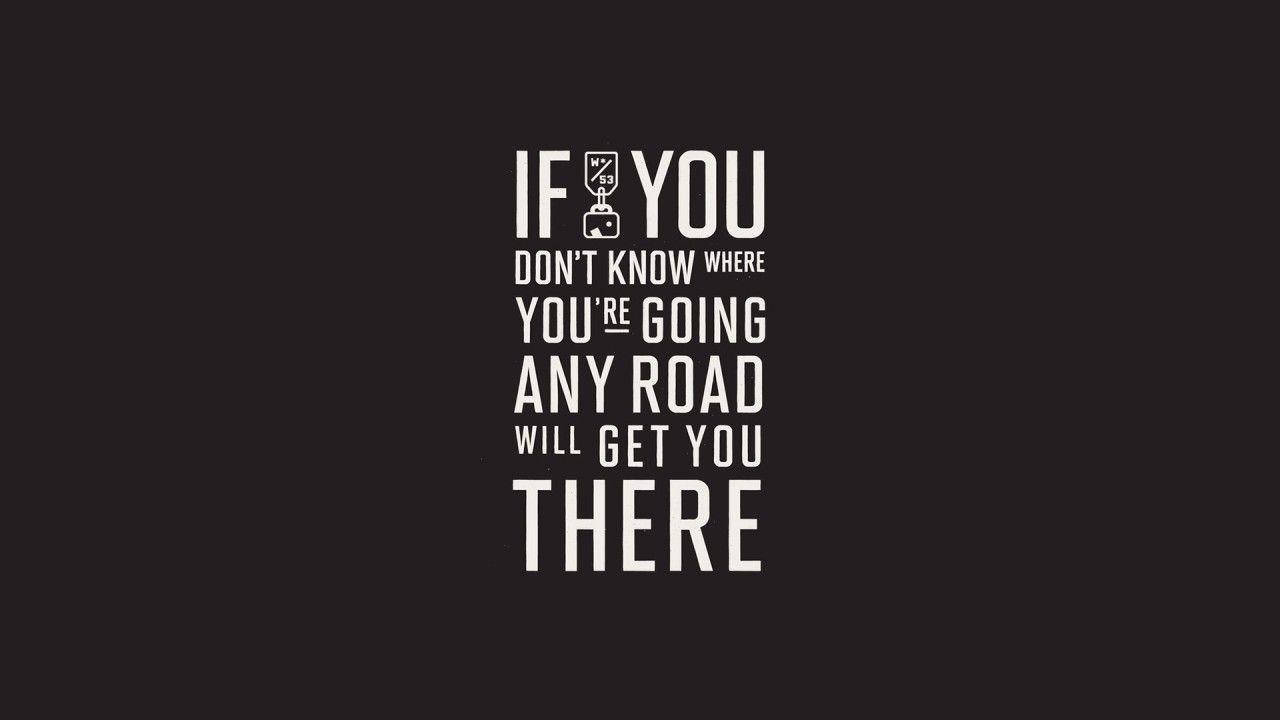 Give 桌布 壁紙 — 黑色背景上粗體白色文字寫著「IF YOU DON'T KNOW WHERE YOU'RE GOING ANY ROAD WILL GET YOU THERE」，並以行李箱圖示取代字母「I」。