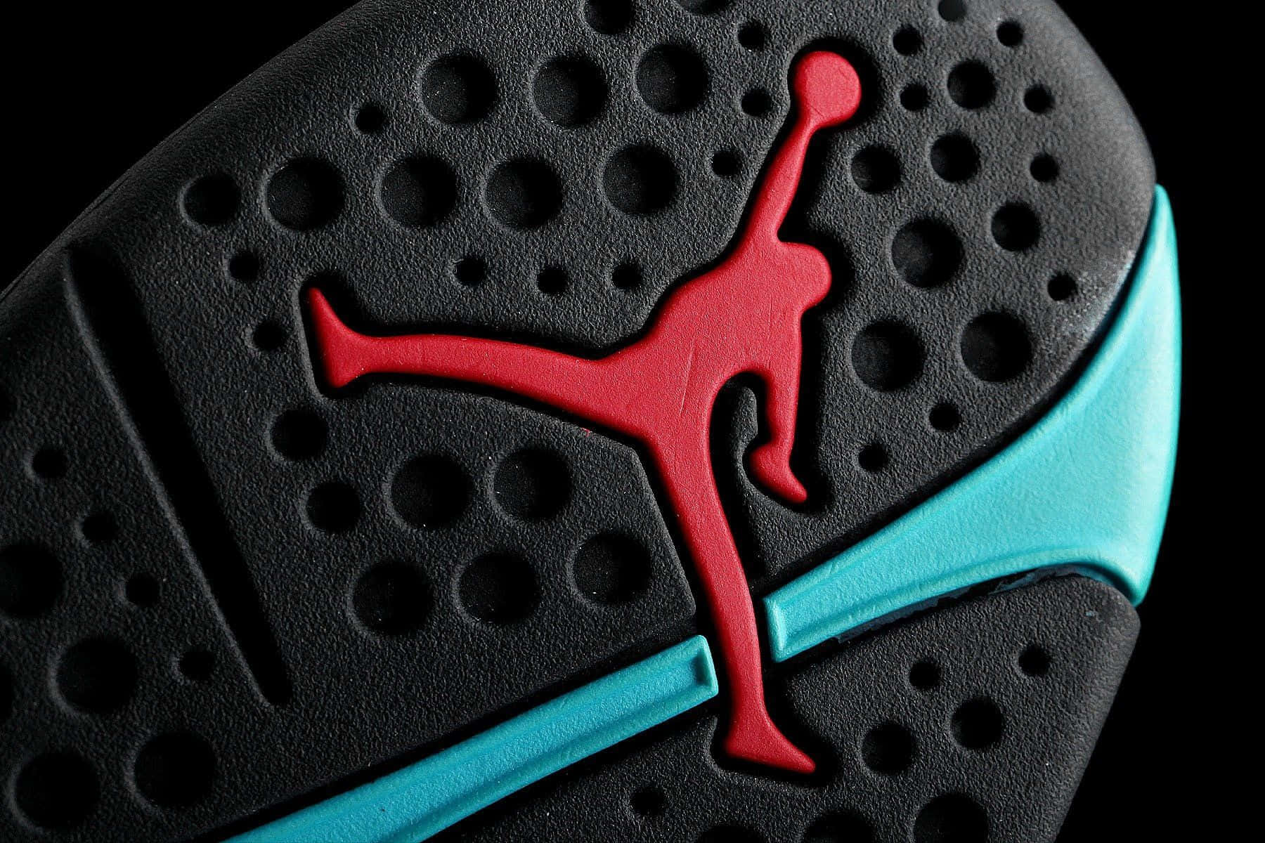 Jordan 桌布 壁紙 — 黑色背景上黑色運動鞋鞋底的特寫，帶有紅色 Jumpman 標誌和藍綠色條紋。