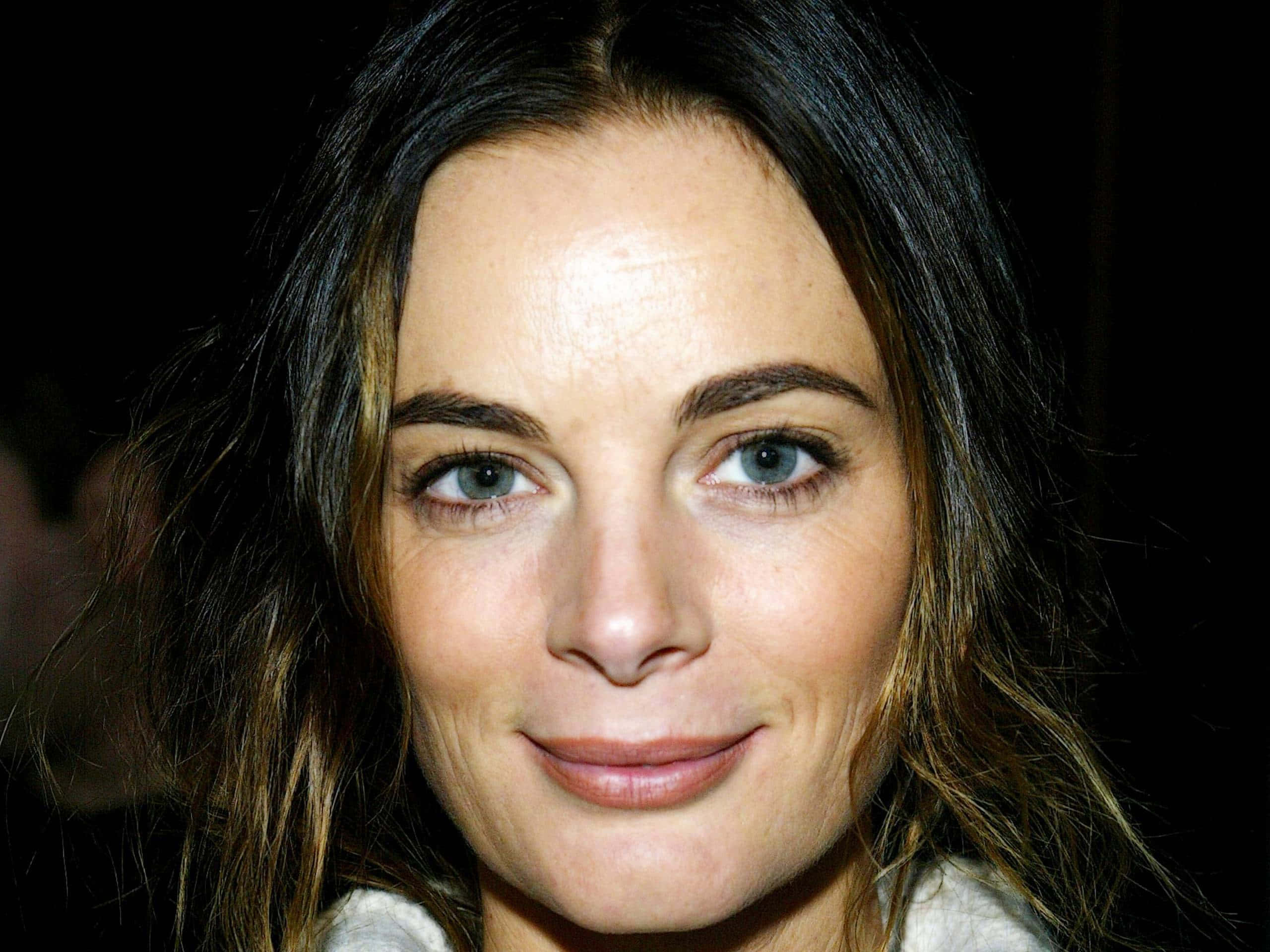 Gabrielle Anwar 桌布 壁紙 — 黑色背景前，一位深色頭髮、藍眼睛的女性柔和微笑的特寫肖像。