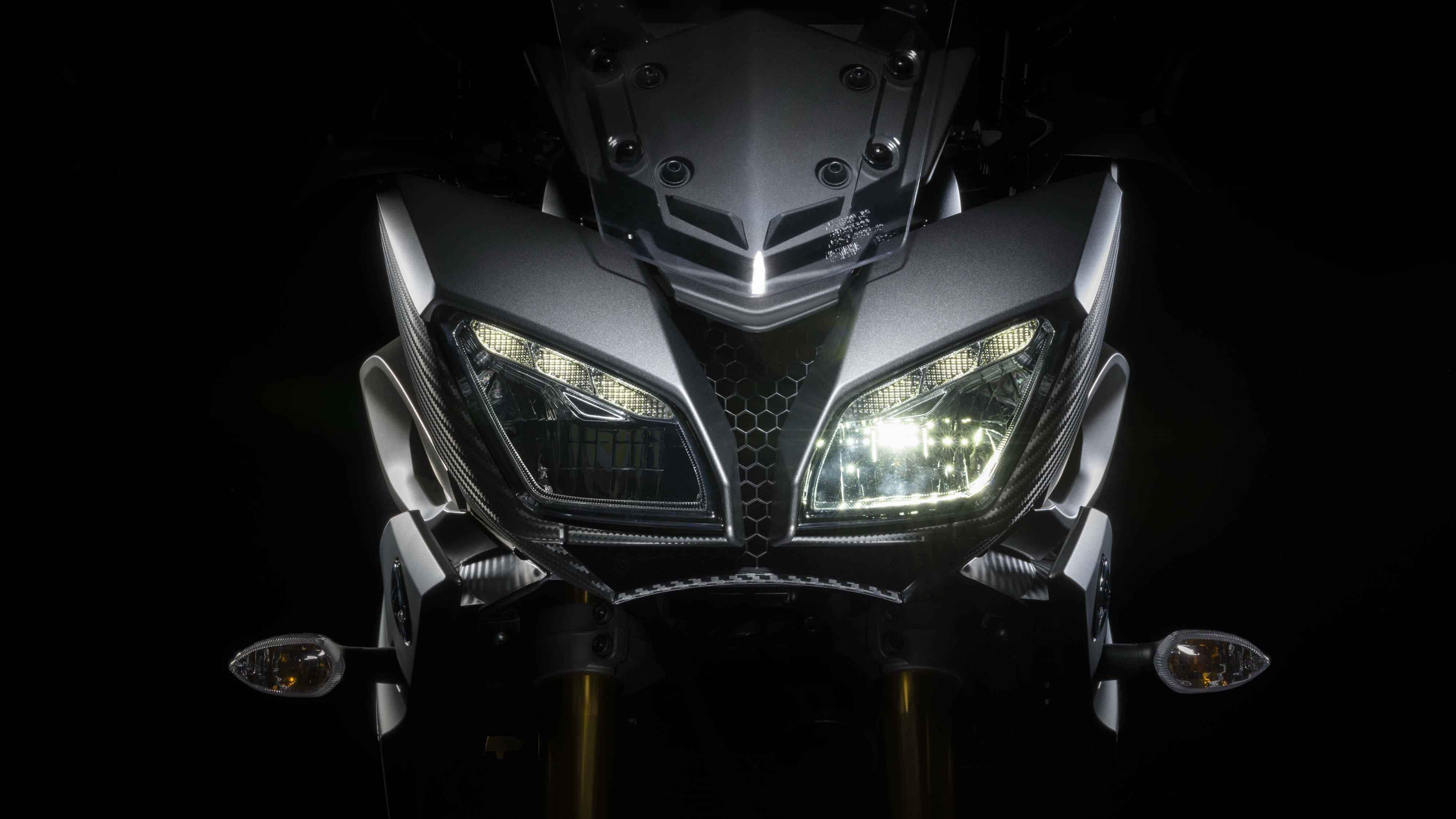 yamaha mt 15 桌布 壁紙 — 黑色背景前，時尚機車發光車頭燈的特寫。