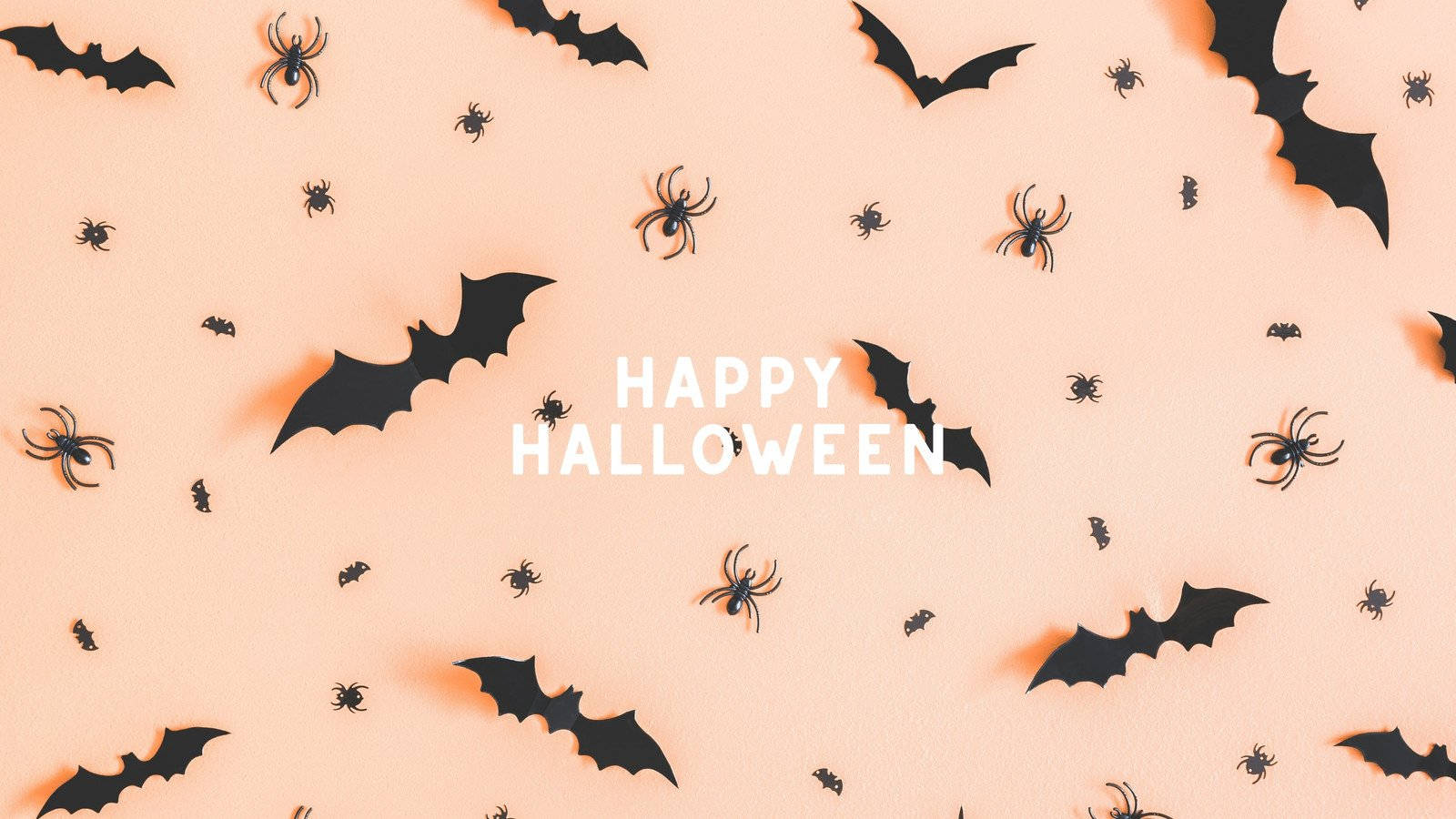 Spooky Season 桌布 壁紙 — 黑色蝙蝠和蜘蛛在柔和的桃色背景上漂浮，並有粗體白色「HAPPY HALLOWEEN」文字。