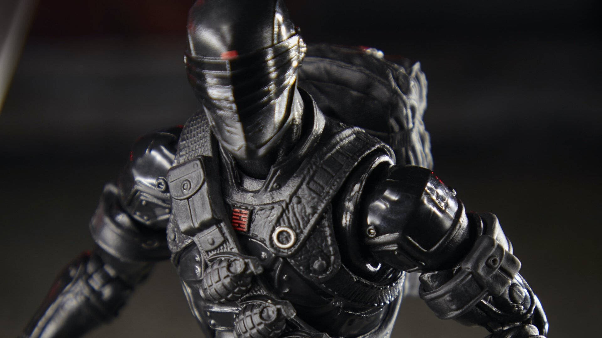Snake Eyes 桌布 壁紙 — 黑色裝甲動作人偶的特寫，戴著面具，帶有紅色點綴，背景為深色模糊。