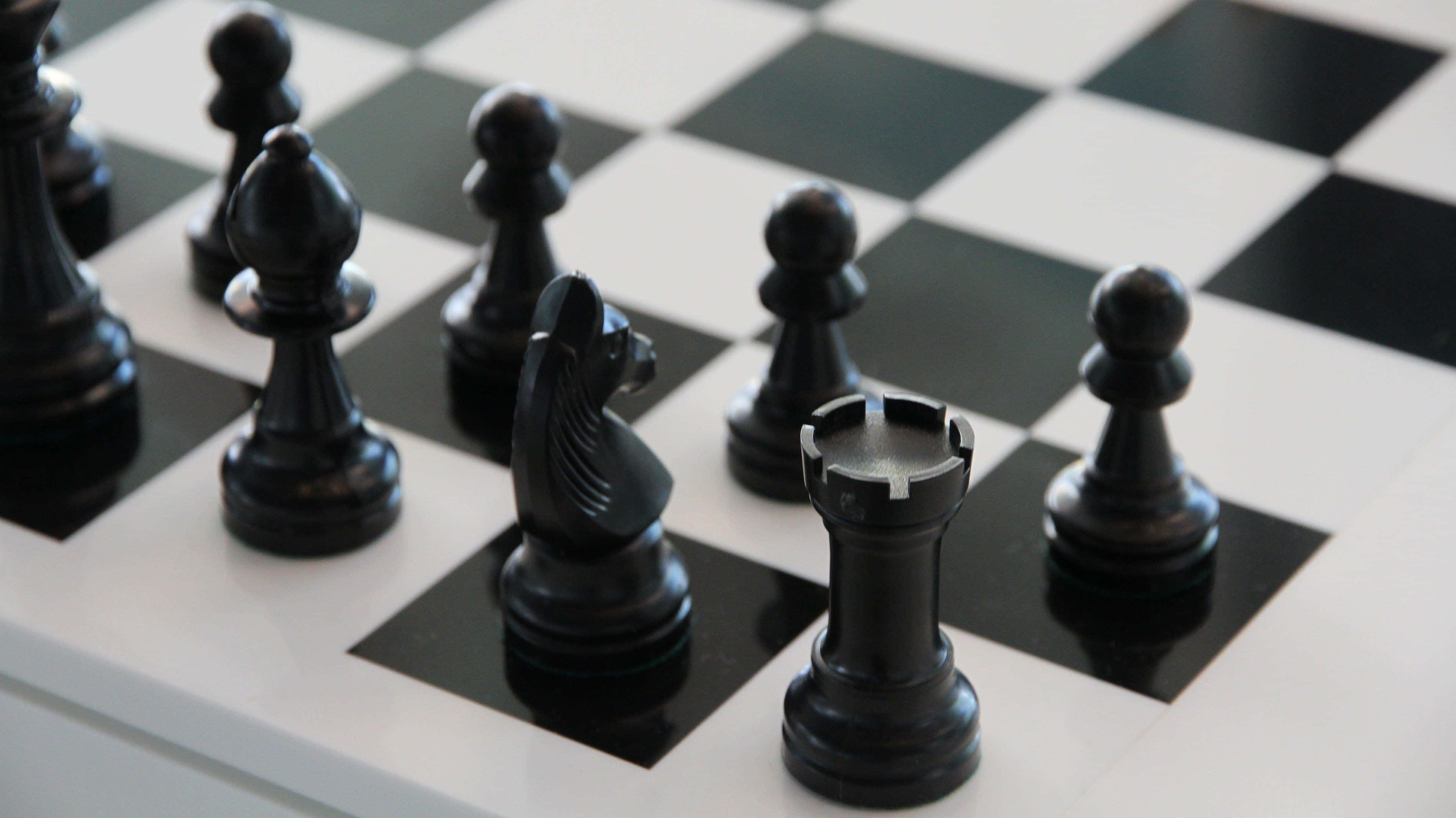 西洋棋 桌布 壁紙 — 黑色西洋棋棋子於棋盤上的特寫，光線柔和，景深較淺。