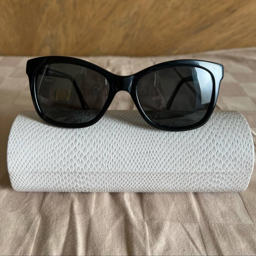 Sunglasses 桌布 壁紙 — 黑色貓眼太陽眼鏡優雅地放在米色布料表面上的白色紋理眼鏡盒上。