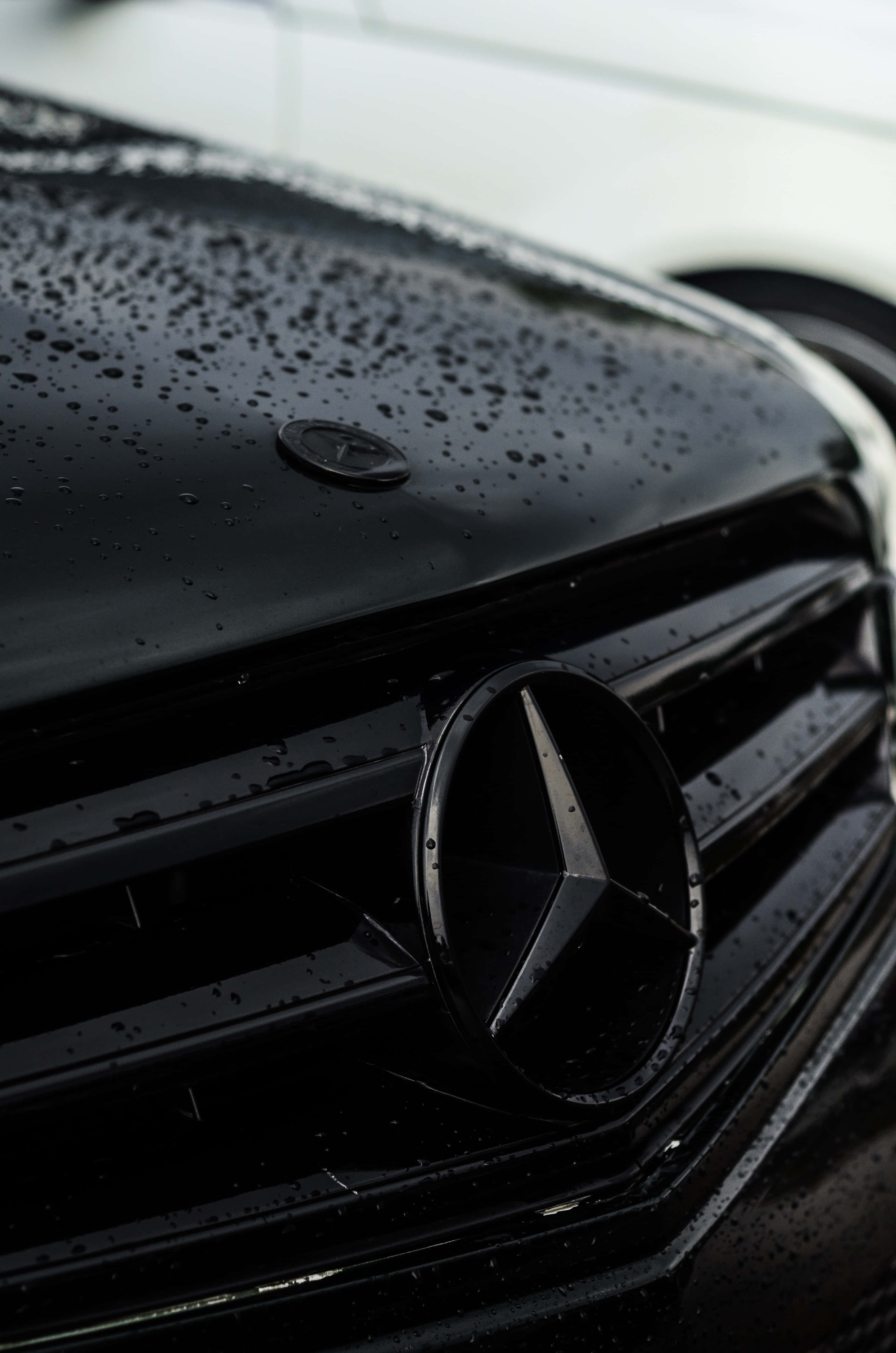 Mercedes 桌布 壁紙 — 黑色賓士水箱護罩的特寫，光滑表面上閃爍著雨滴。