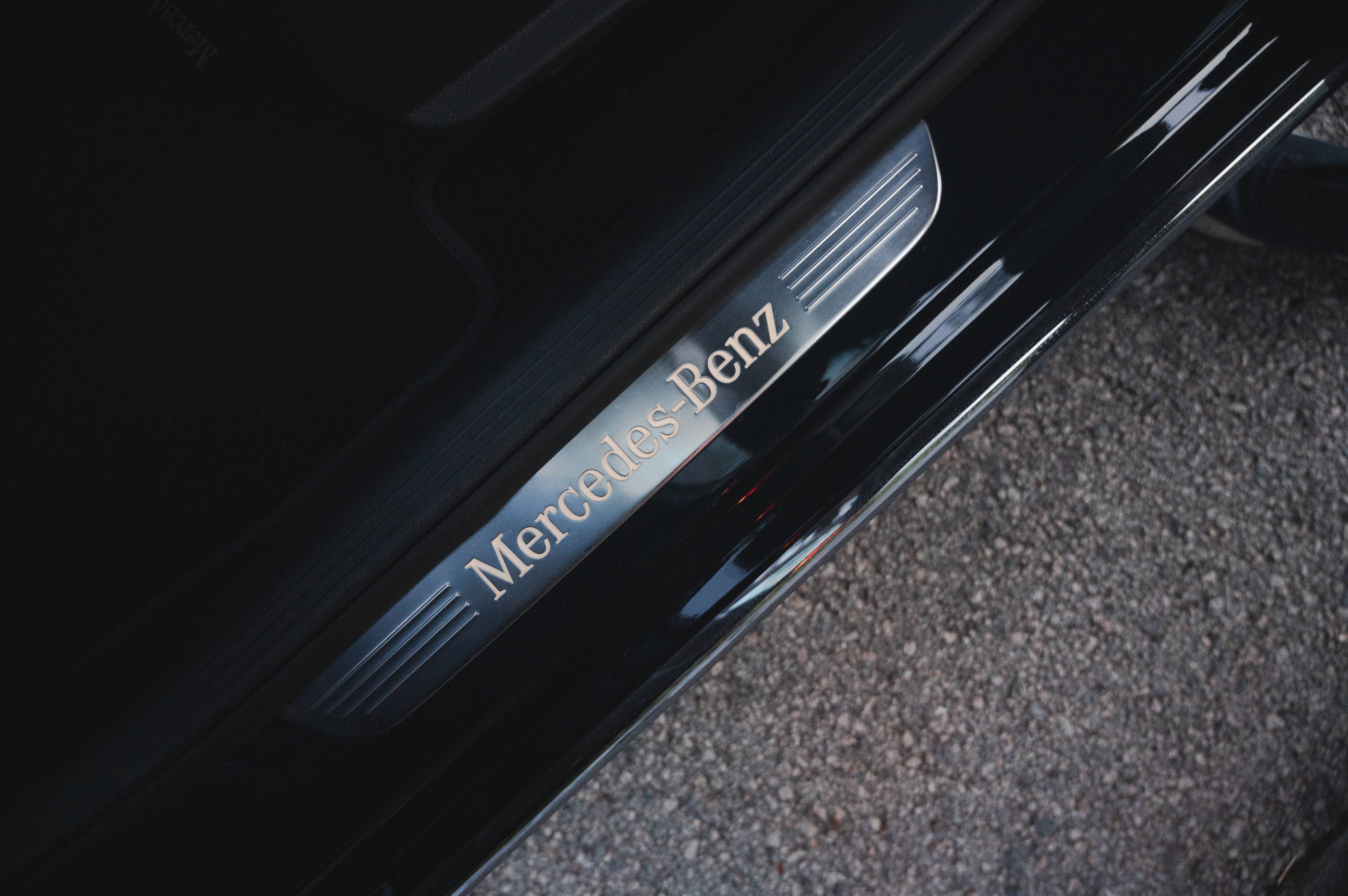 Mercedes Amg 桌布 壁紙 — 黑色賓士門檻板特寫，在柔和光線下於碎石地面上閃耀。