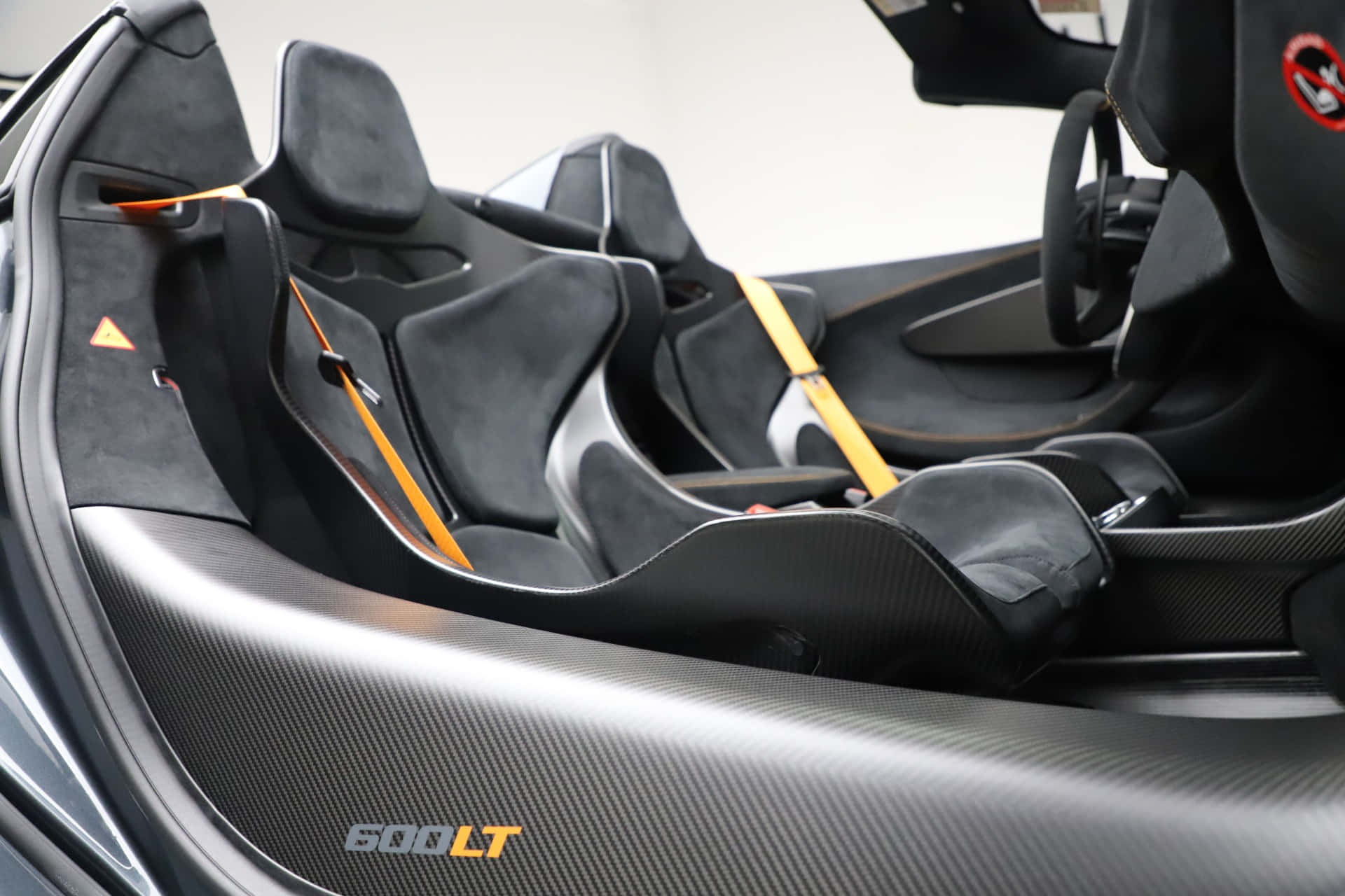 Mclaren 600lt Spider 桌布 壁紙 — 黑色跑車內飾特寫，採用碳纖維飾邊和鮮豔的橙色安全帶。