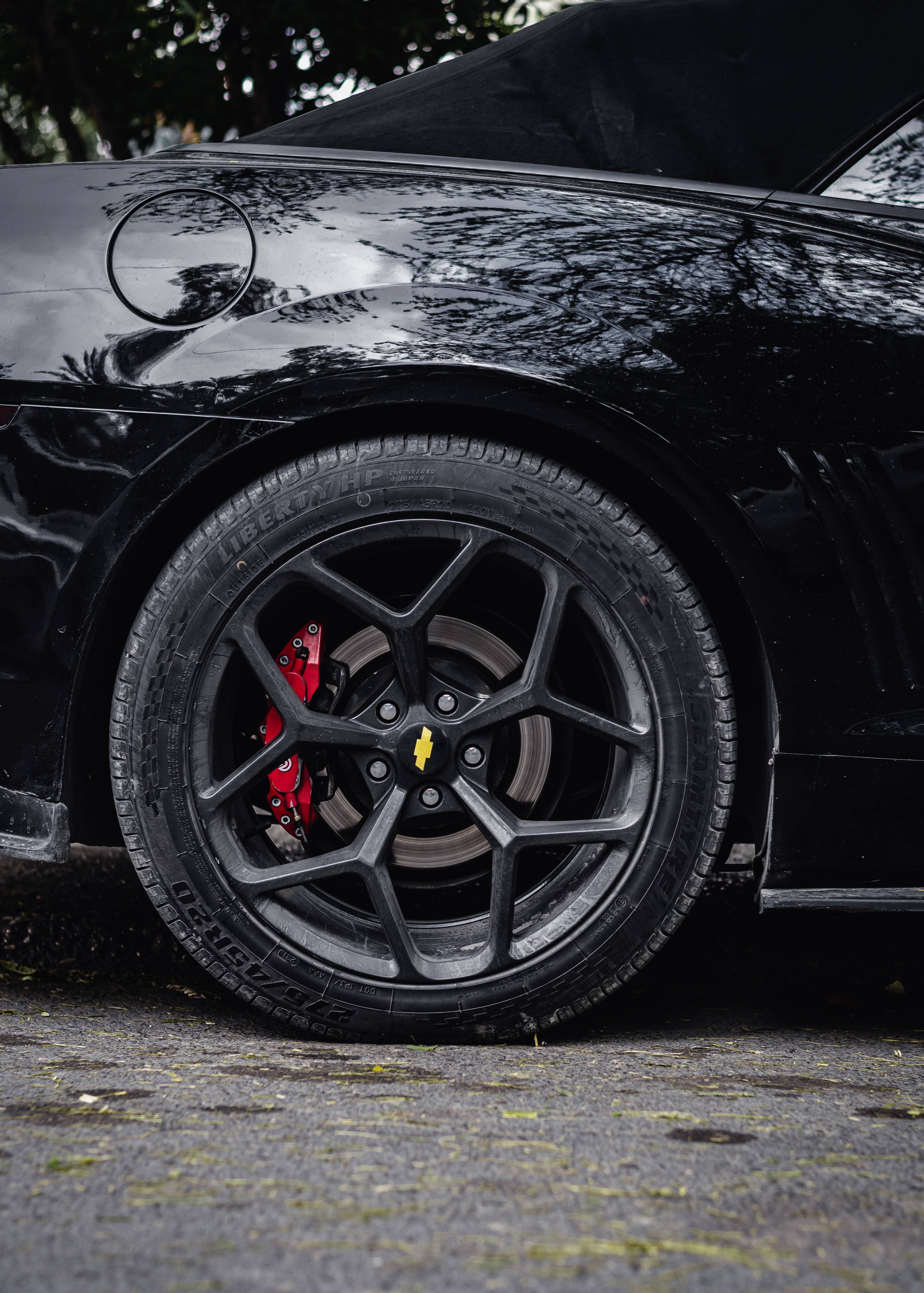 Chevrolet 桌布 壁紙 — 黑色跑車車輪特寫，配紅色制動卡鉗，光面處理反射樹木。