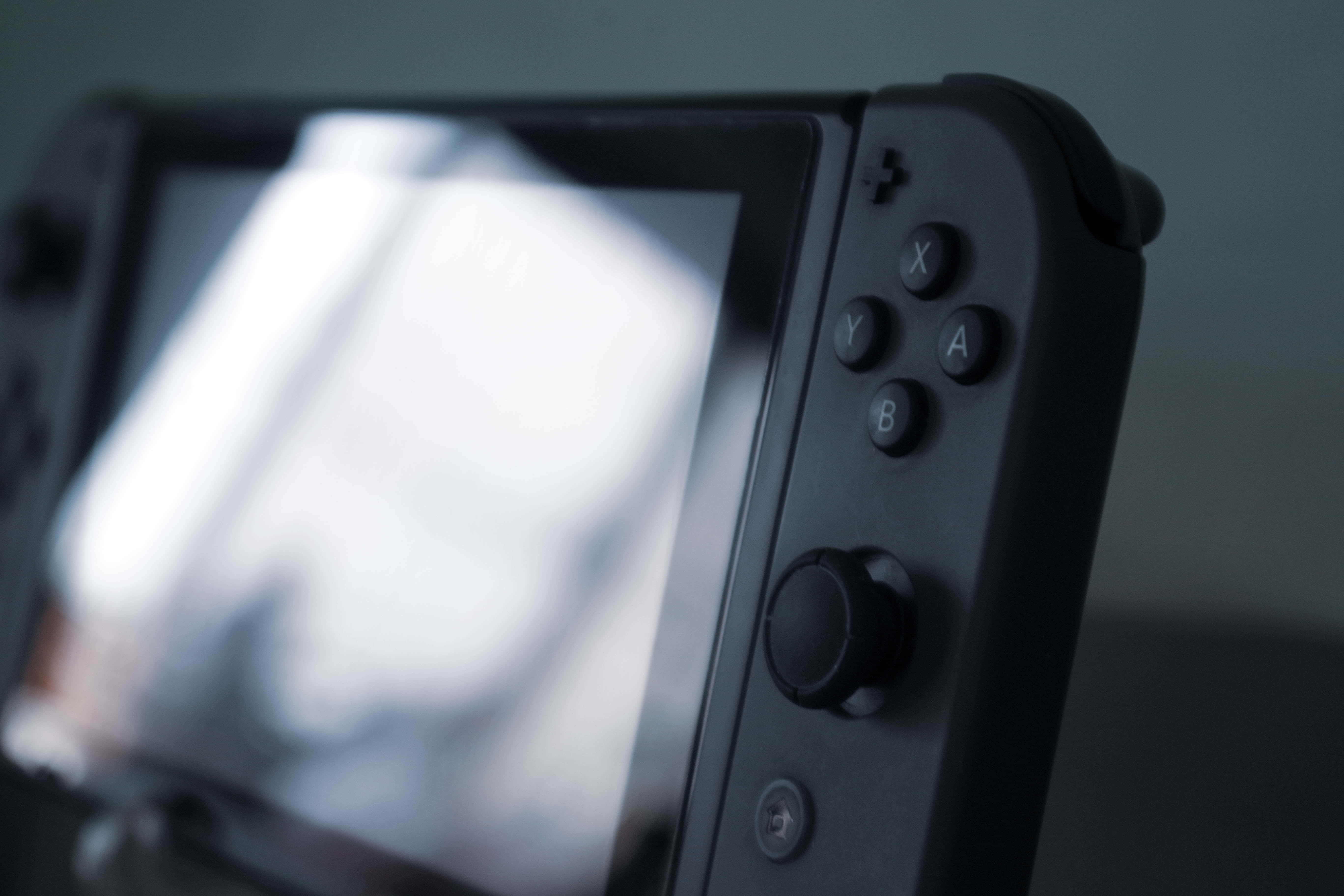 Gaming Consoles 桌布 壁紙 — 黑色遊戲機手把的特寫，帶有按鈕和螢幕，柔焦效果。