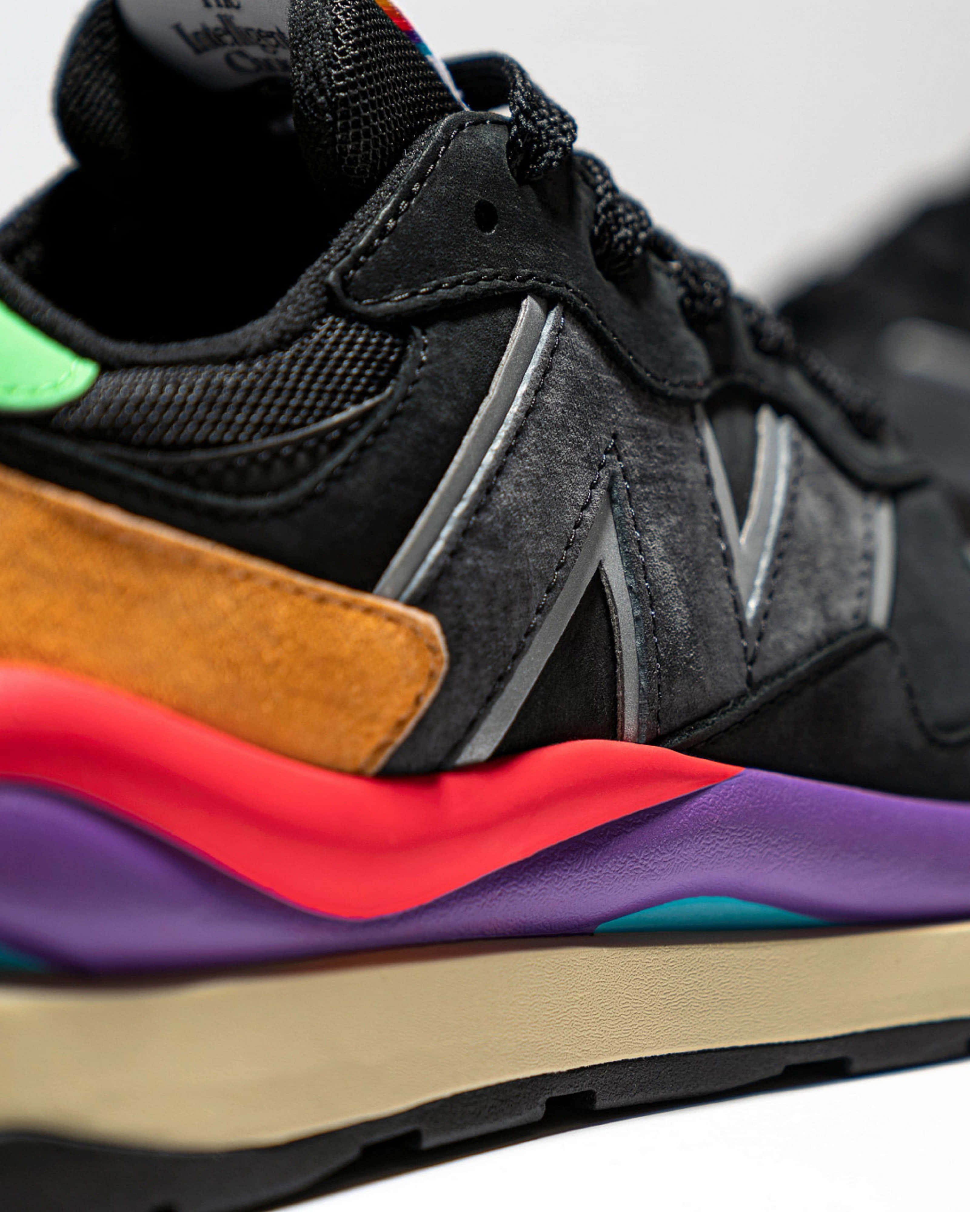 New Balance 桌布 壁紙 — 黑色運動鞋的特寫，帶有充滿活力的多色層疊鞋底和螢光綠色鞋跟標籤。