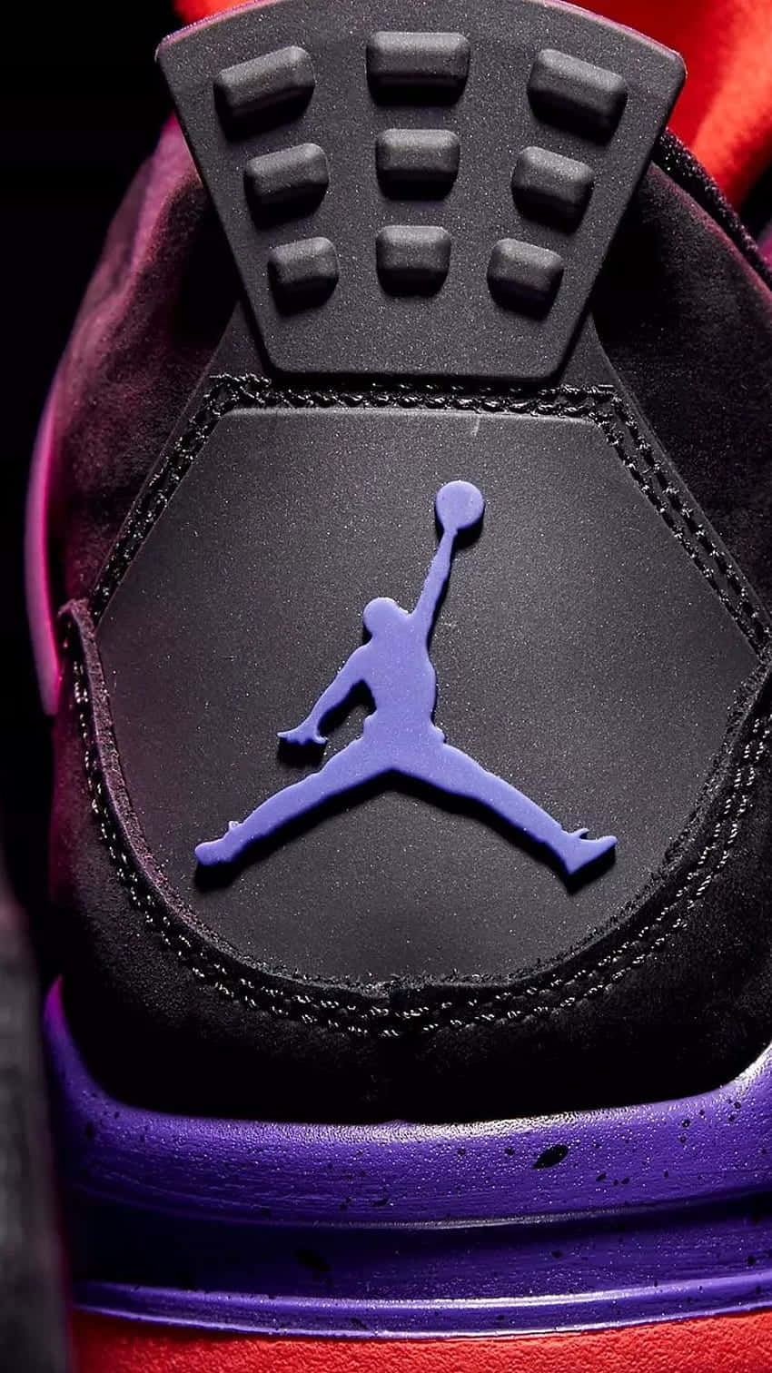 Jordan Logo Phone 桌布 壁紙 — 黑色運動鞋鞋跟的特寫，帶有紫色 Jumpman 標誌和紅色點綴，在戲劇性燈光下。