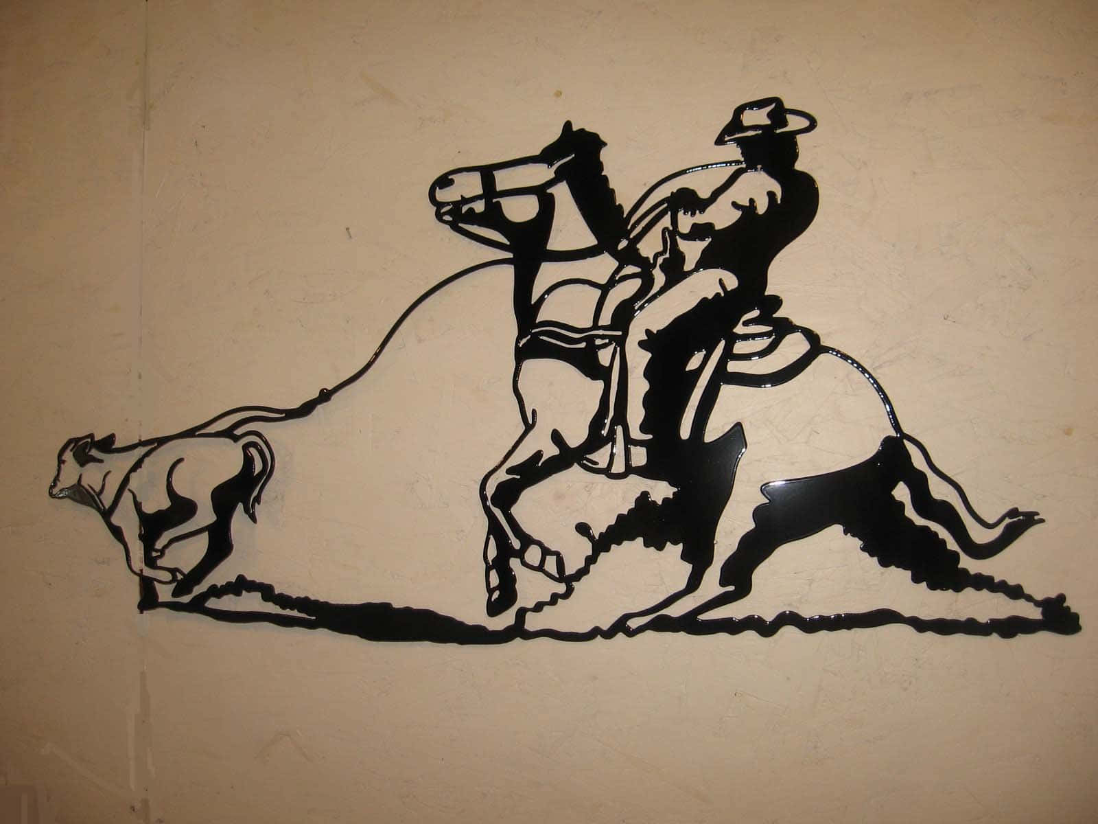 Roping 桌布 壁紙 — 黑色金屬剪影，描繪牛仔騎馬追逐公牛，背景為米色牆壁。