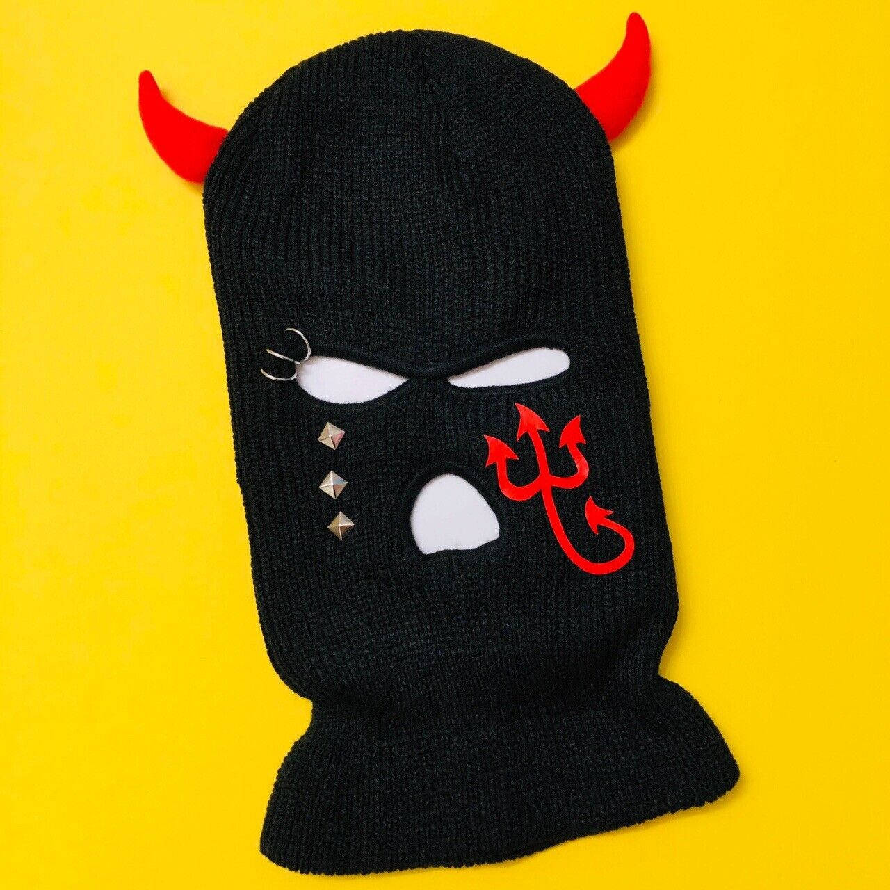 Black Ski Mask 桌布 壁紙 — 黑色針織巴拉克拉法帽，帶紅色惡魔角和三叉戟，背景為亮黃色。