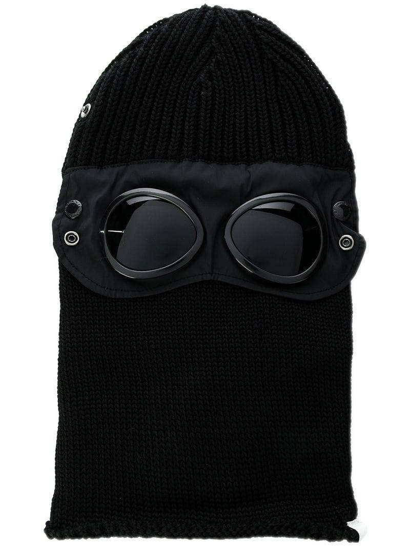 Sunglasses 桌布 壁紙 — 黑色針織巴拉克拉法帽，配備一體式護目鏡，帶有反光鏡片和金屬鉚釘，背景為白色。