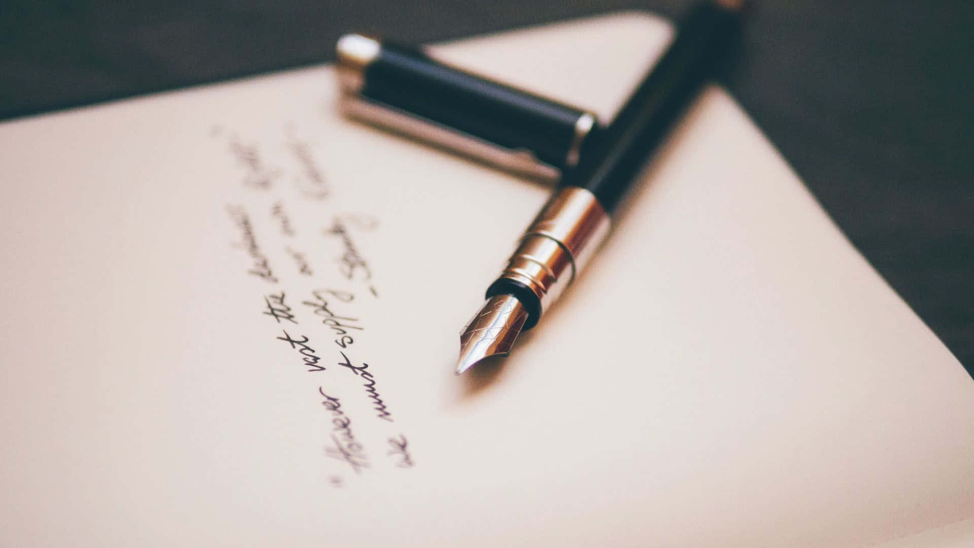 Writing 桌布 壁紙 — 黑色鋼筆的特寫，放在奶油色紙上，紙上有手寫草書文字。