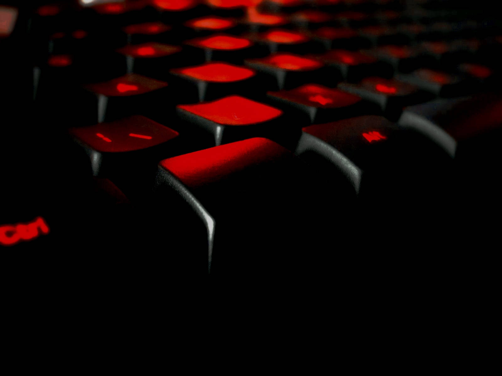 科技動圖 桌布 壁紙 — 黑色鍵盤特寫，帶有發光紅色背光，背景為深色。