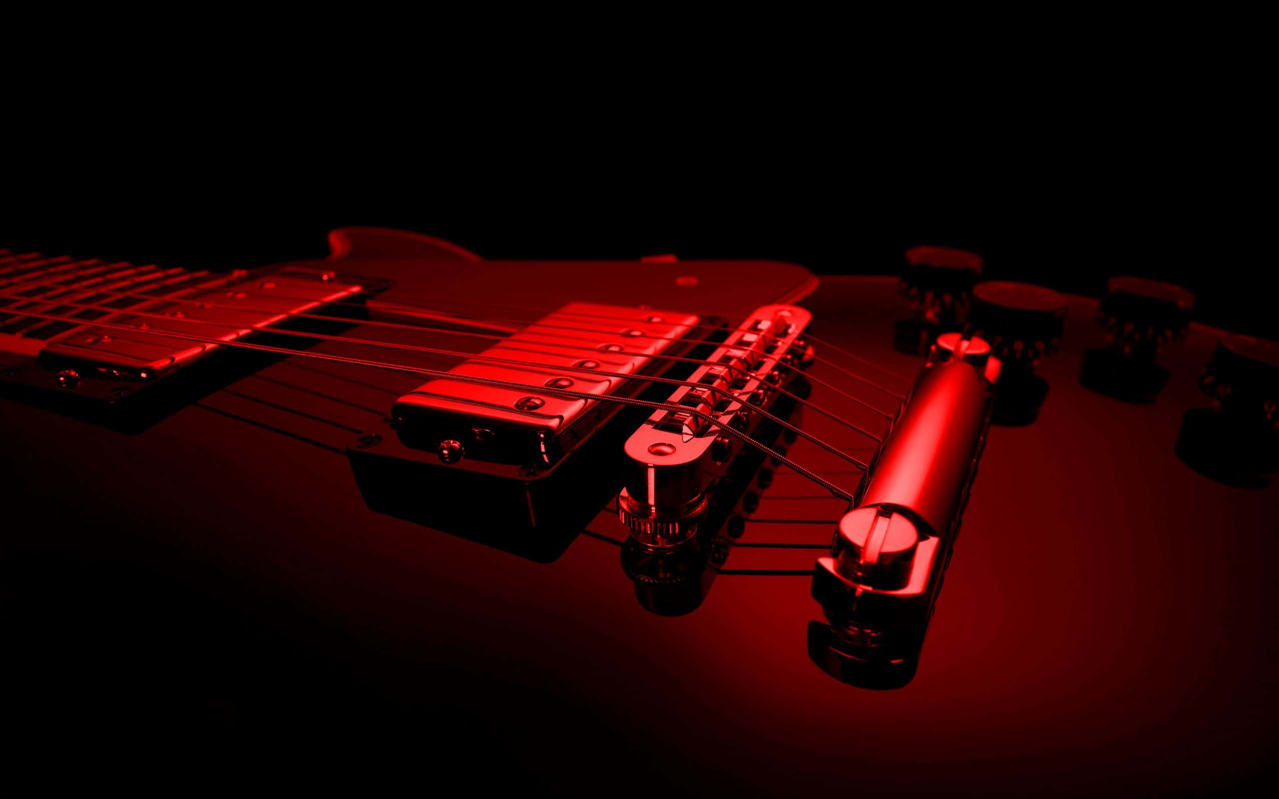 Guitar Aesthetic 桌布 壁紙 — 黑色電吉他在黑暗背景下被戲劇性的紅光籠罩的特寫。