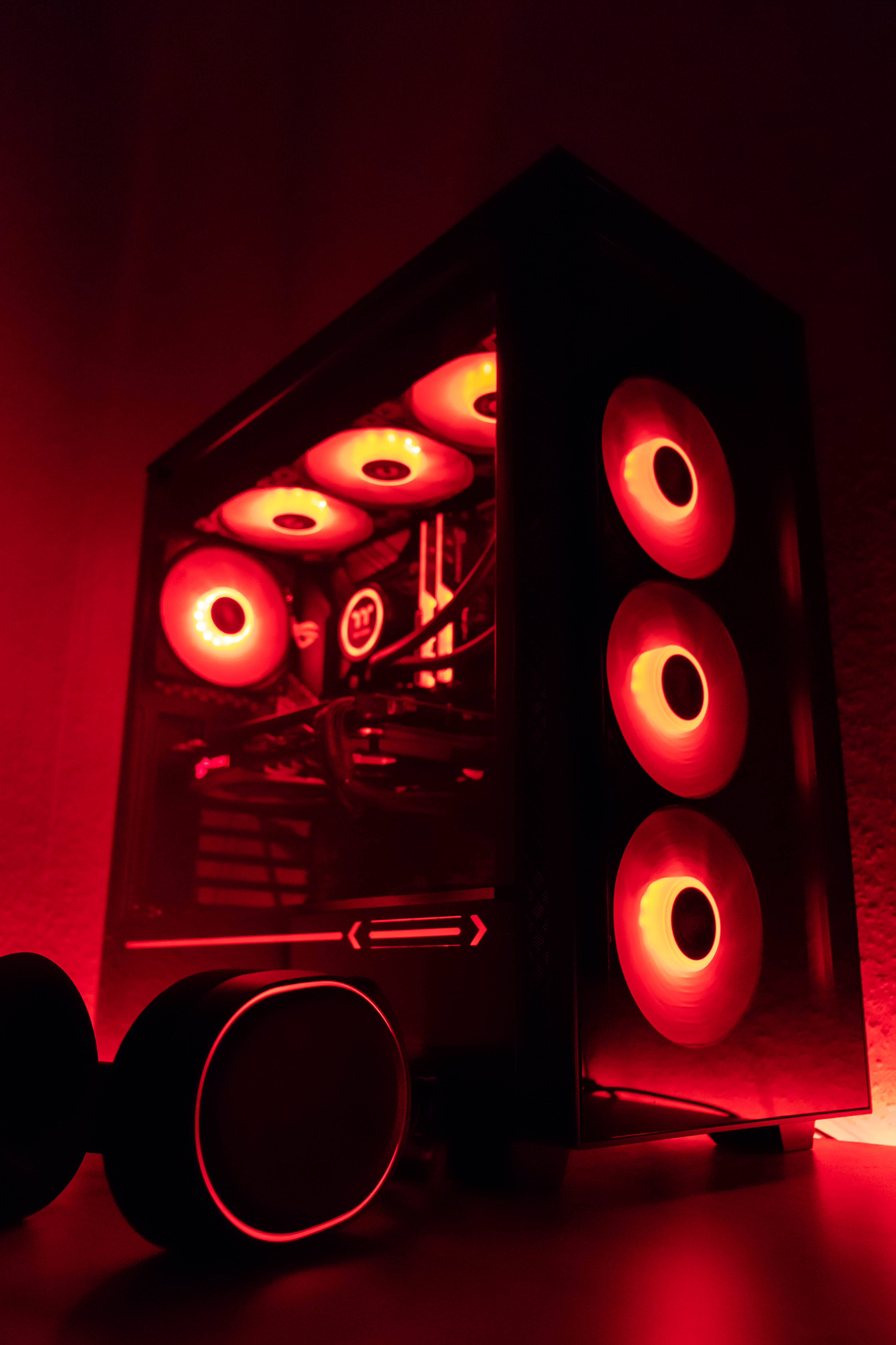 msi 2560x1080 桌布 壁紙 — 黑色電腦機殼帶有發光紅色風扇和內部照明，在黑暗表面上投射出溫暖的環境光。