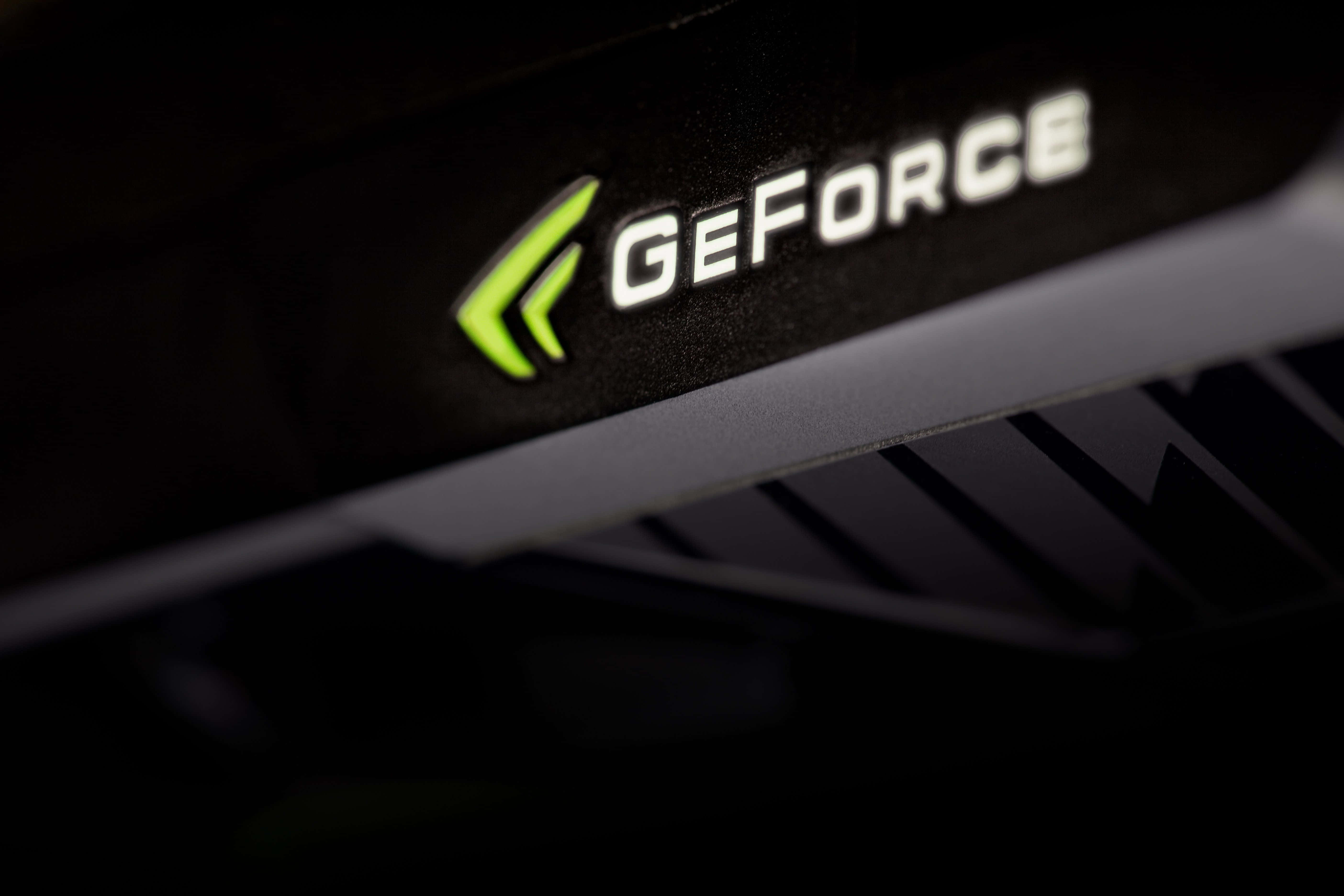 Nvidia 4K UHD 桌布 壁紙 — 黑色顯示卡上發光綠色 GeForce 標誌的特寫，帶有鋒利的金屬邊緣。