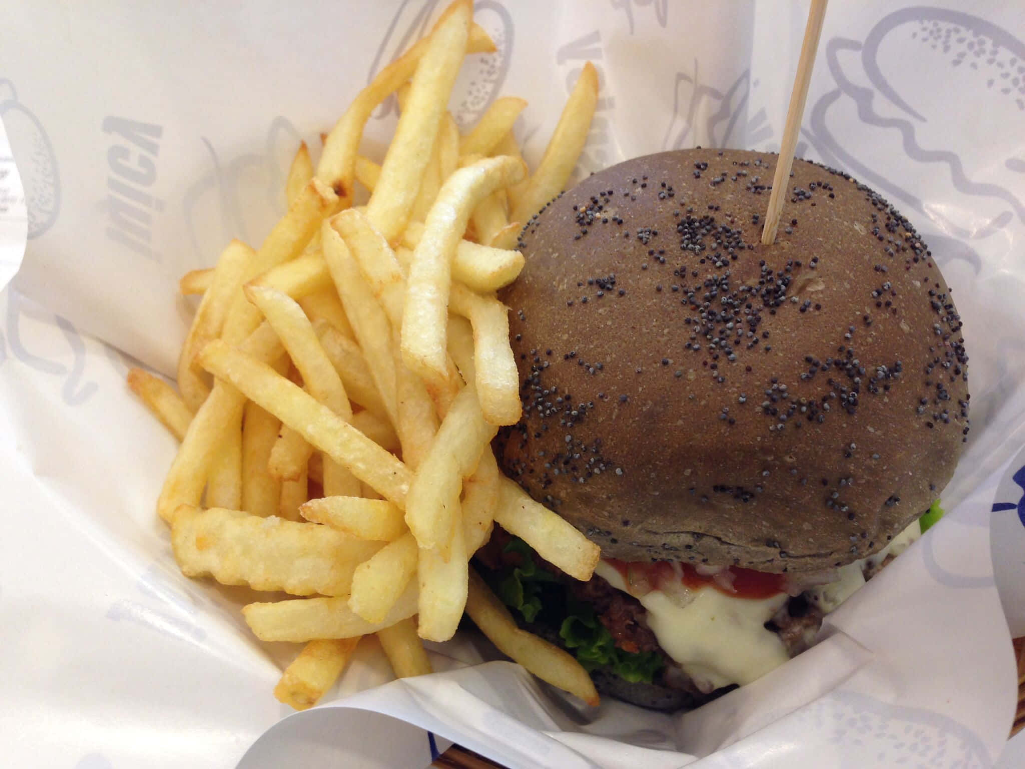 fast food 桌布 壁紙 — 黑芝麻麵包漢堡搭配融化起司和薯條，放在品牌紙中的特寫。