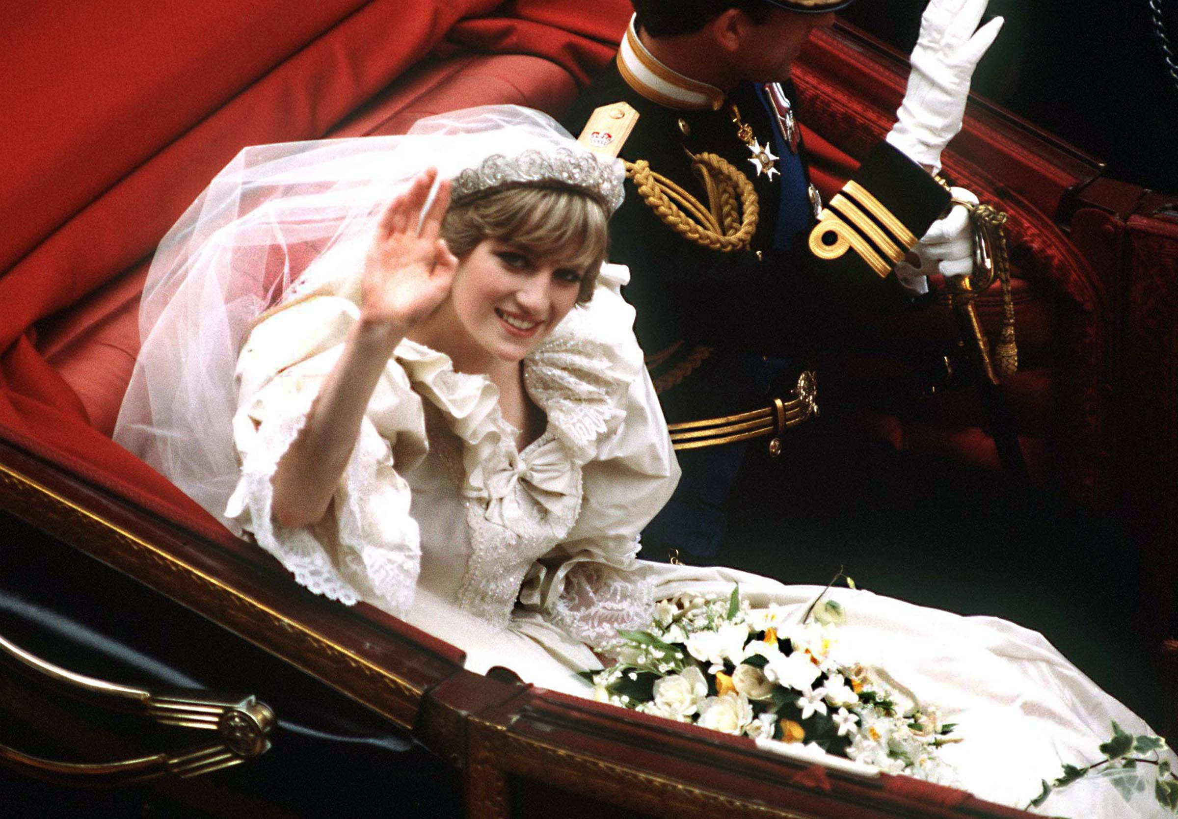 Princess 桌布 壁紙 — 黛安娜王妃從一輛紅色天鵝絨馬車上愉快地揮手，一名身穿制服的衛兵站在她身旁。
