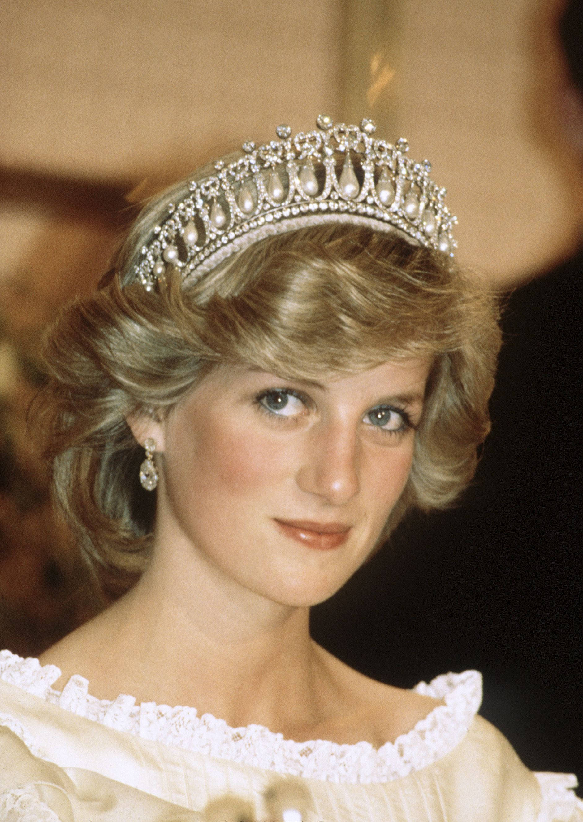 Princess 桌布 壁紙 — 黛安娜王妃溫柔地凝視，戴著閃爍的鑽石头飾和珍珠耳環，身穿奶油色蕾絲連衣裙。