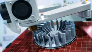 3D列印機在紅色網格床上創建一個灰色的風扇形狀物體。 — 3D 壁紙