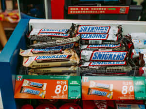 貨架上的 Snickers 巧克力棒，附有中文價格標籤。 — 桌面 壁紙