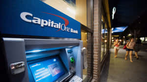 夜晚城市人行道上的 Capital One 自動櫃員機，有行人經過。 — 人物 壁紙