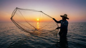 漁夫在日落時撒網入海