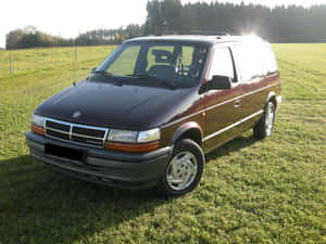 栗色Dodge Caravan停放在日落時的草地上 — 克萊斯勒 壁紙