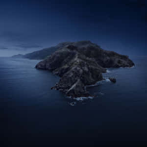 在繁星點點的夜空下，海洋中的岩石島嶼。 — 暮光 壁紙