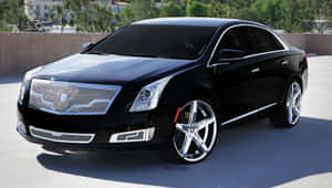 黑色 Cadillac XTS 豪華轎車，帶有鍍鉻細節，在明亮的陽光下停放在戶外。 — 凱迪拉克 壁紙
