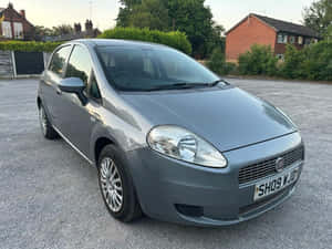 黃昏時分，灰色 Fiat Punto 停放在磚房附近的碎石地上。 — 飛雅特 壁紙