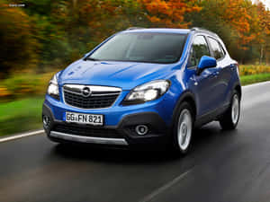 藍色 Opel Mokka SUV 在秋天的森林中行駛。 — 歐寶 壁紙