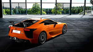 橙色 Lexus LFA 跑車在室內展示，附森林景色。 — 凌志 壁紙