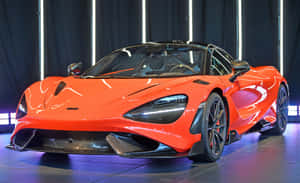 橙色McLaren跑車展示，帶有發光的燈光和後面的深色窗簾。 — MacBook Air M1 壁紙