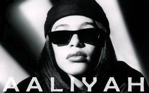 Aaliyah 戴著太陽眼鏡和毛帽，帶有粗體文字疊加。 — 艾莉亞·巴特 壁紙