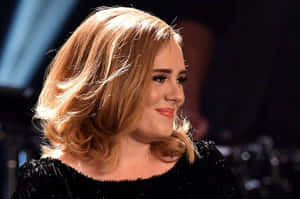 Adele 穿著黑色亮片上衣在舞台上微笑，金色頭髮。 — 愛黛兒 壁紙